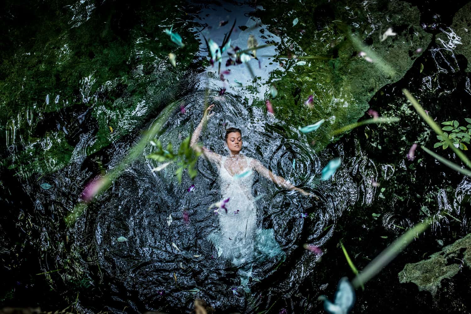 wedding portrait of a bride floating in a cenote in mexico